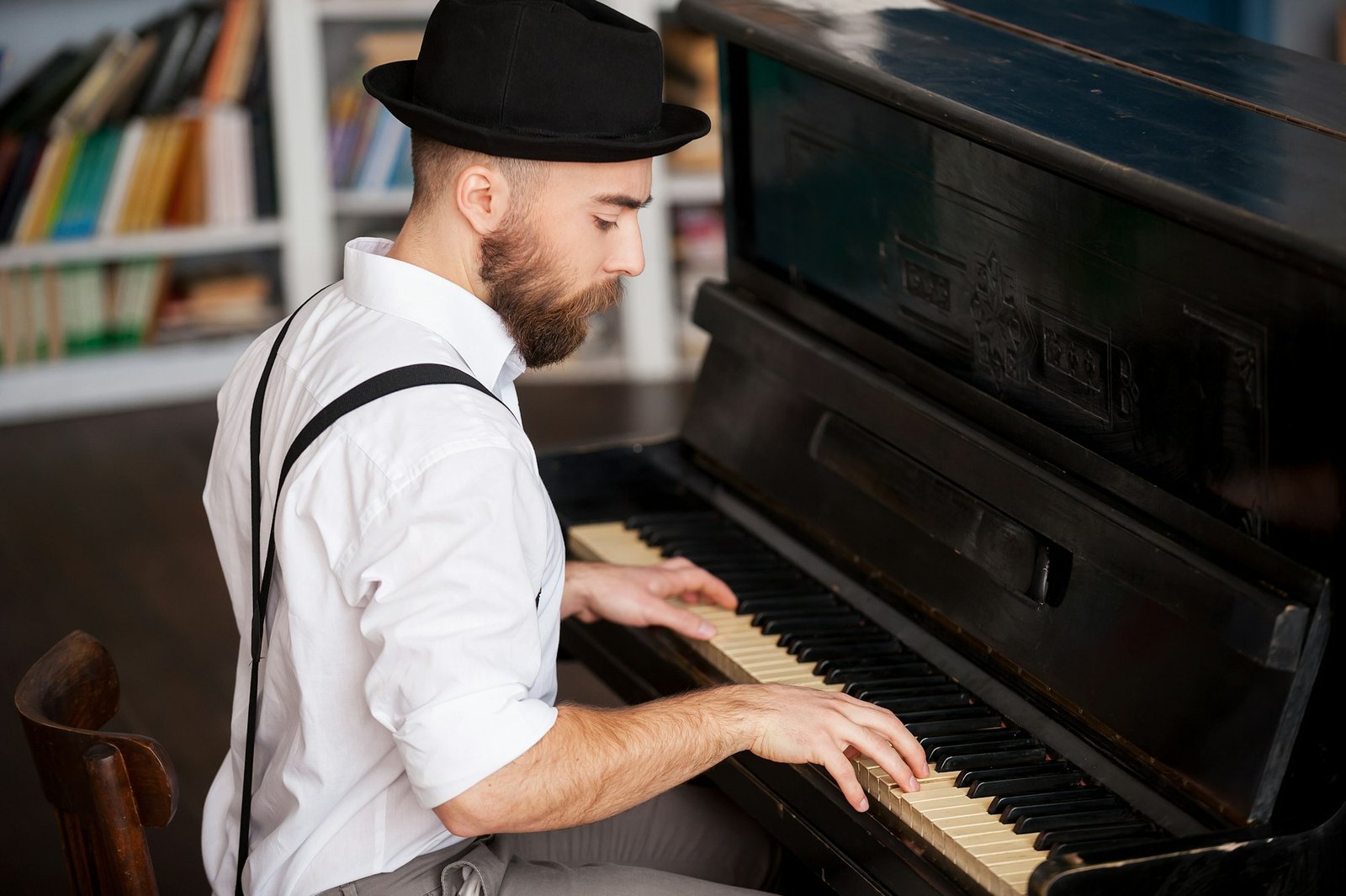 Making music. Profile of a handsome young bearded men playing piano